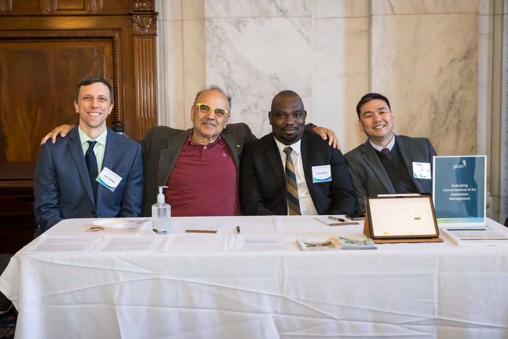 Kevin Lybarger, Farrokh Alemi, K. Pierre Eklou, and Vladimir Franzuela Cardenas at the project table, with a PCORI sign reading Evaluating Conversational AI for Depression Management